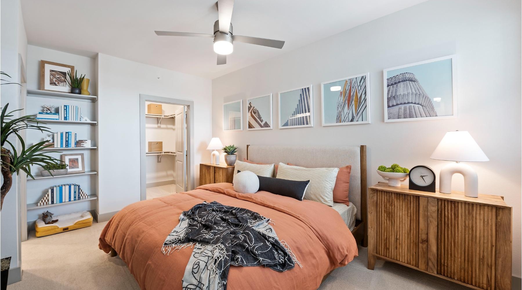 bedroom with bed ceiling fan side tables and lamps and view of a closet